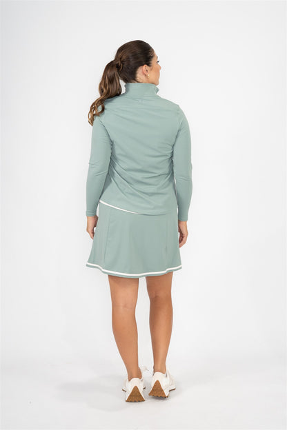 Woman wearing Fairway Green quarter-zip pullover and matching Fairway Green wrap skort with white trim, shown from the back with hair in a ponytail. Streamlined and performance-ready women’s golf apparel designed for movement, comfort, and a polished silhouette.