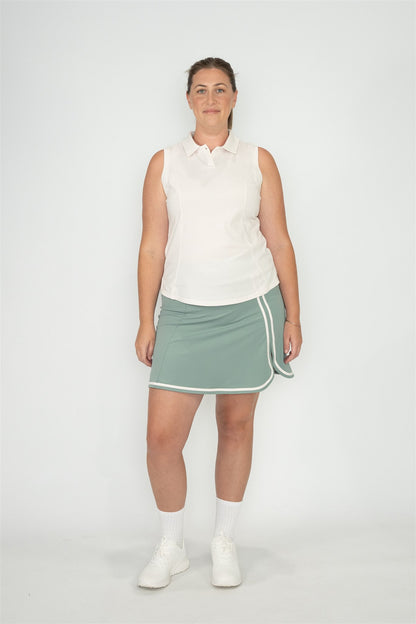 Mid size woman wearing white sleeveless polo and Fairway Green skort with white trim, standing front-facing against plain white background. Elegant and functional women’s golf apparel designed for stylish and active players of all sizes.