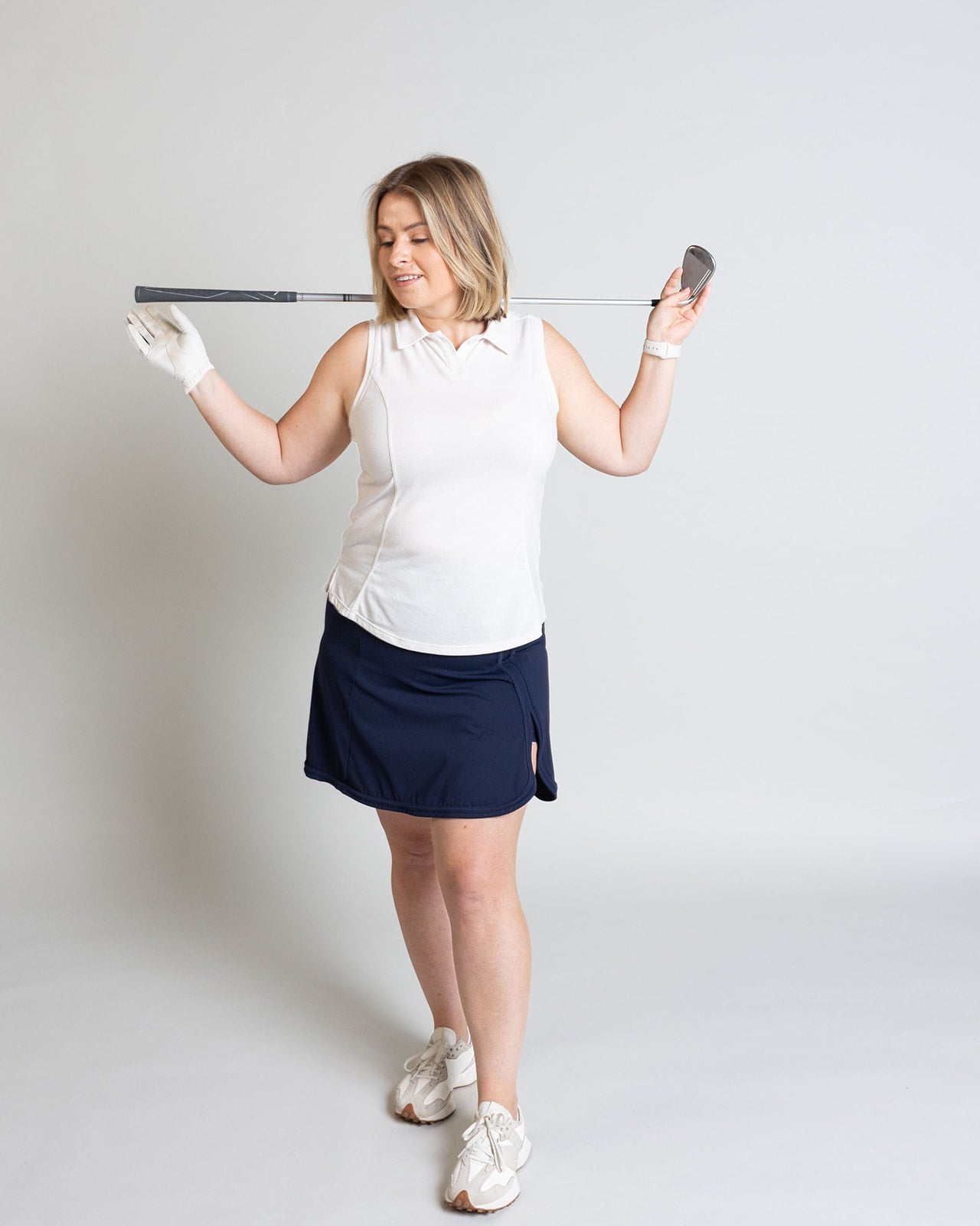 Woman holding a golf club against a plain background