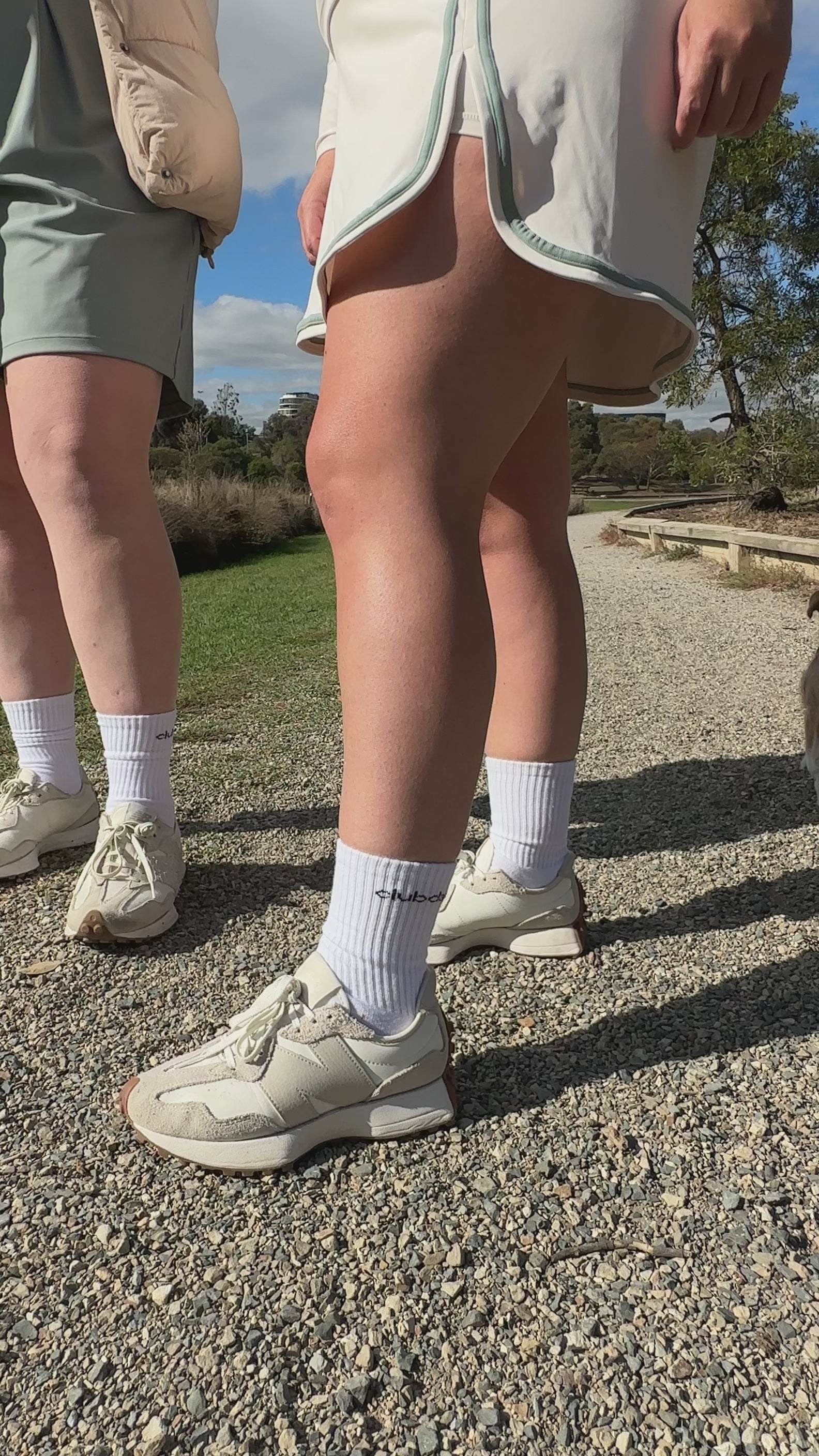 Two Women standing in golf wear and white crew socks. 